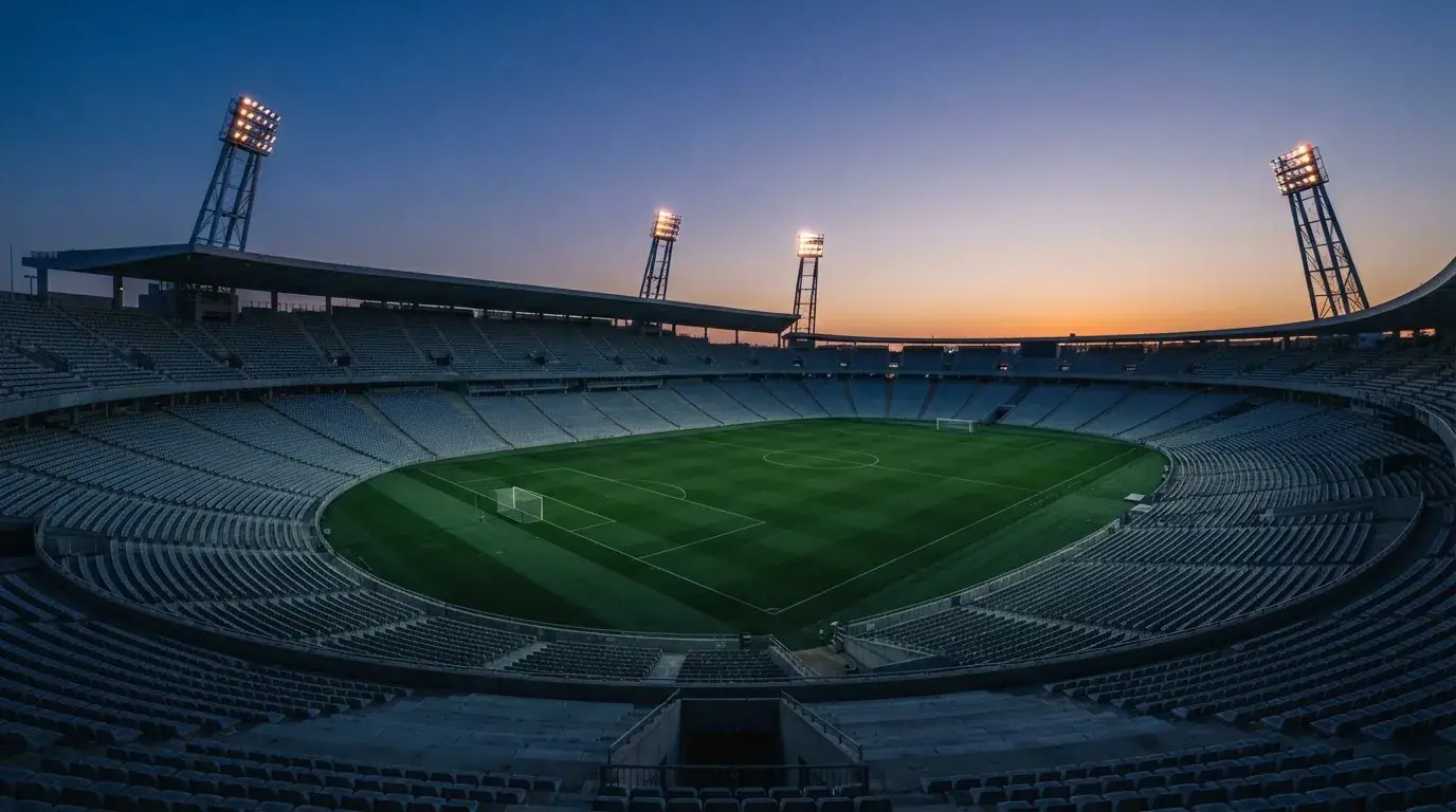 An empty football stadium with floodlight masts at dusk