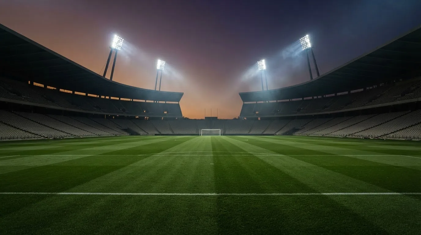 An empty football stadium with floodlight masts at dusk