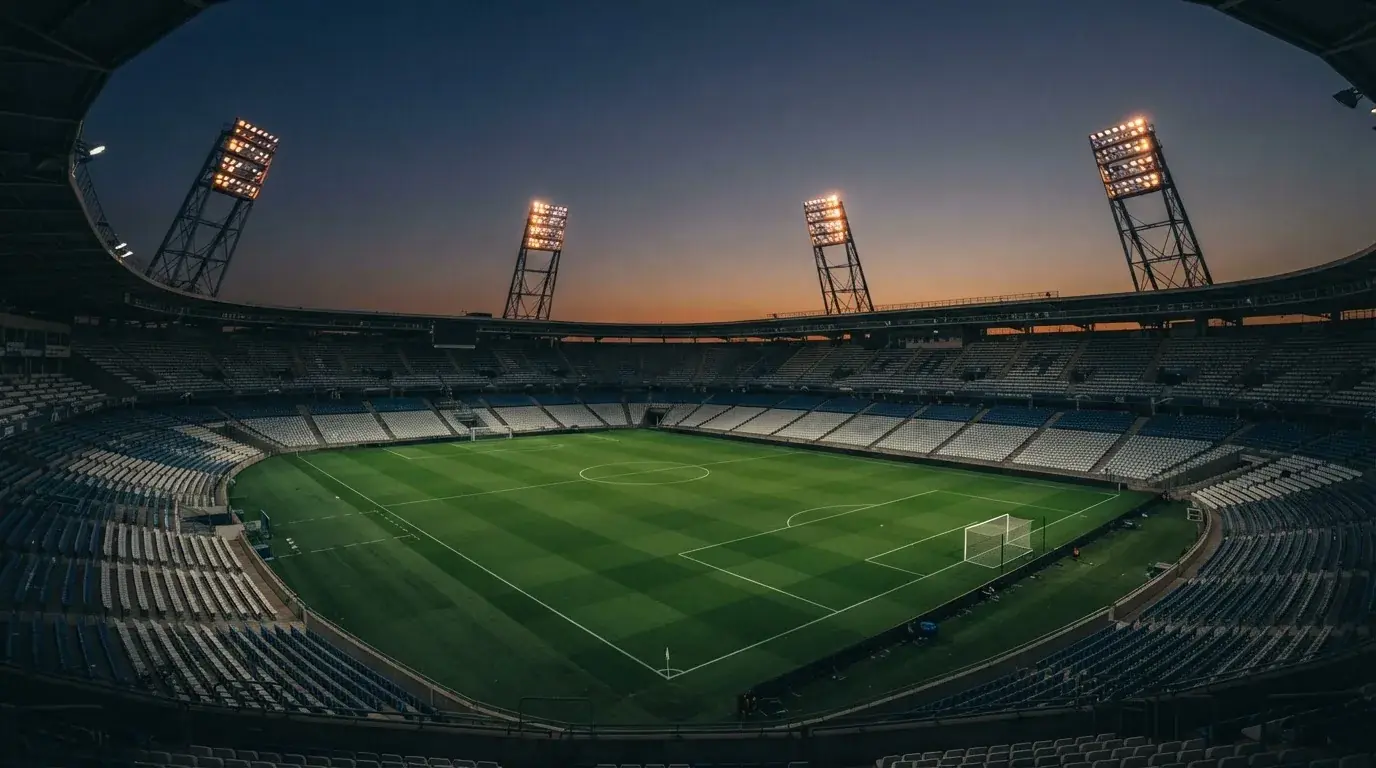 An empty football stadium with floodlight masts at dusk