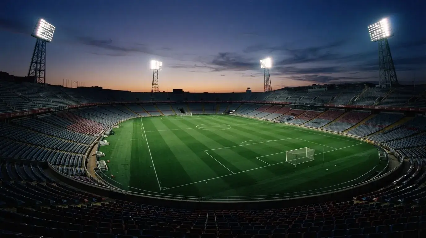 An empty football stadium with floodlight masts at dusk
