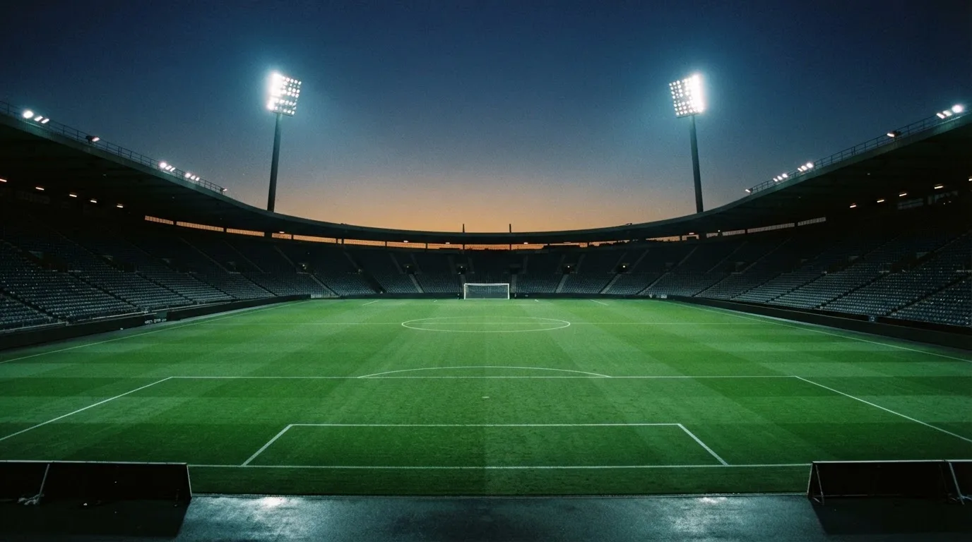 An empty football stadium with floodlight masts at dusk