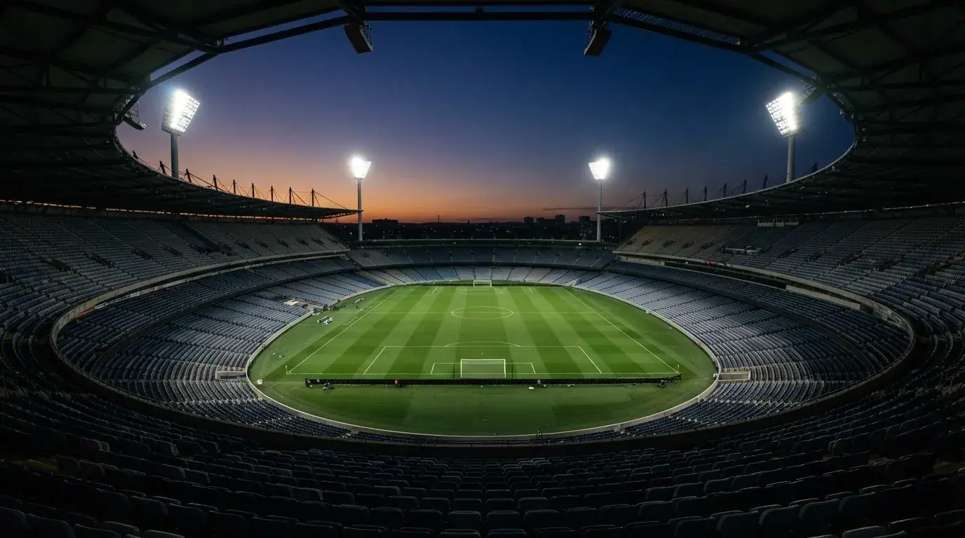 An empty football stadium with floodlight masts at dusk
