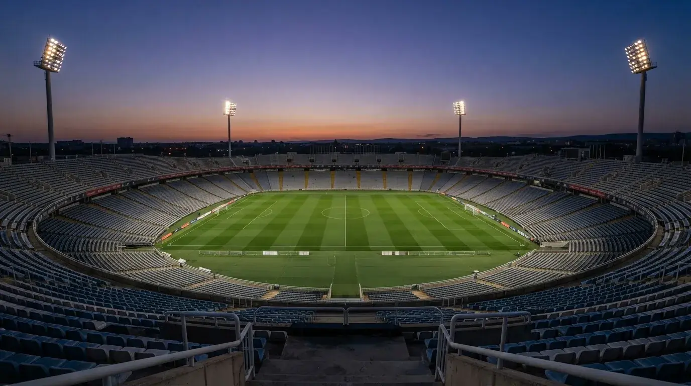 An empty football stadium with floodlight masts at dusk