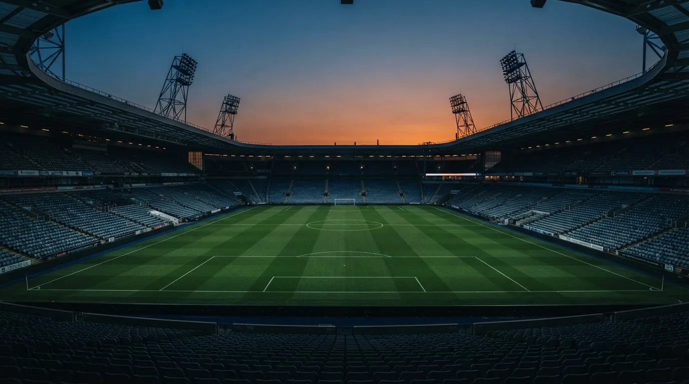 An empty football stadium with floodlight masts at dusk