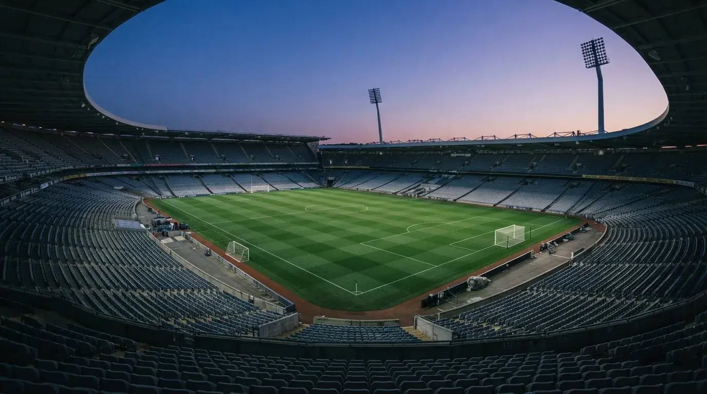 An empty football stadium with floodlight masts at dusk