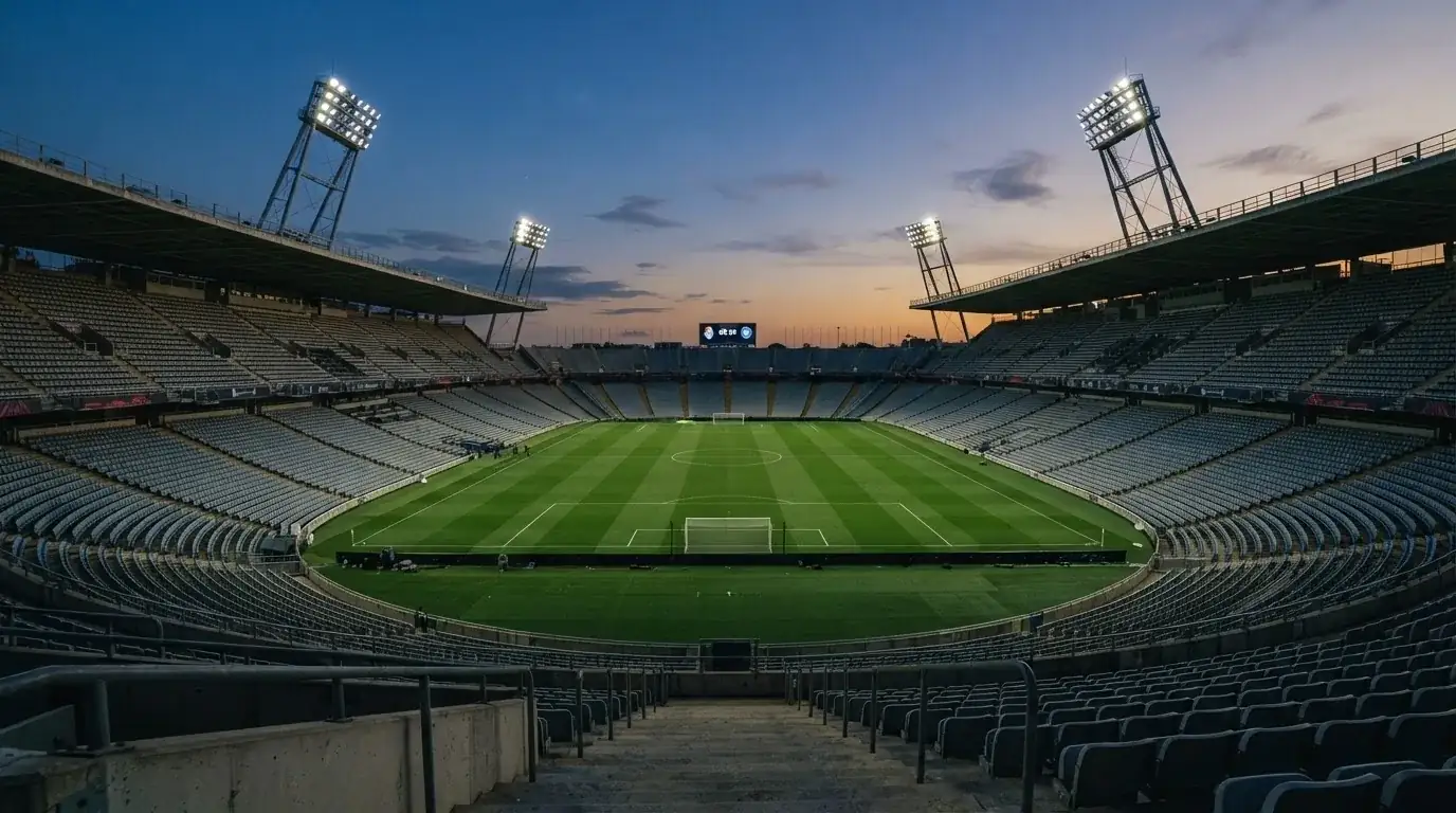 An empty football stadium with floodlight masts at dusk