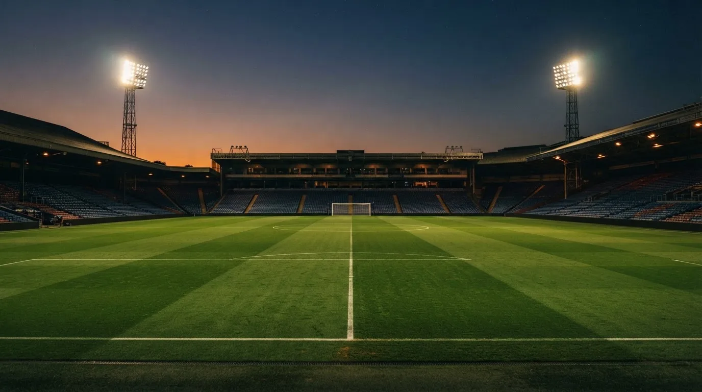 An empty football stadium with floodlight masts at dusk